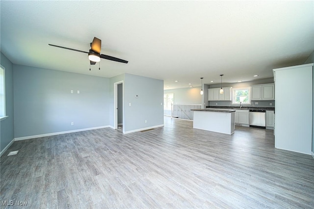 unfurnished living room with ceiling fan, sink, and light hardwood / wood-style flooring