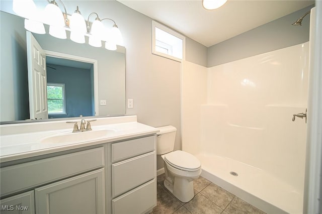 bathroom featuring walk in shower, vanity, toilet, and tile patterned flooring