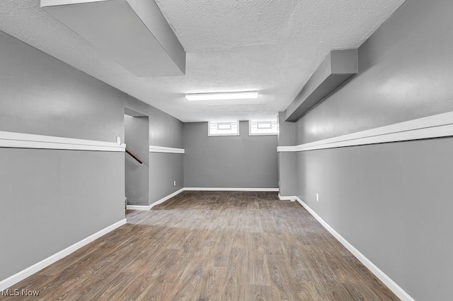 basement with hardwood / wood-style floors and a textured ceiling