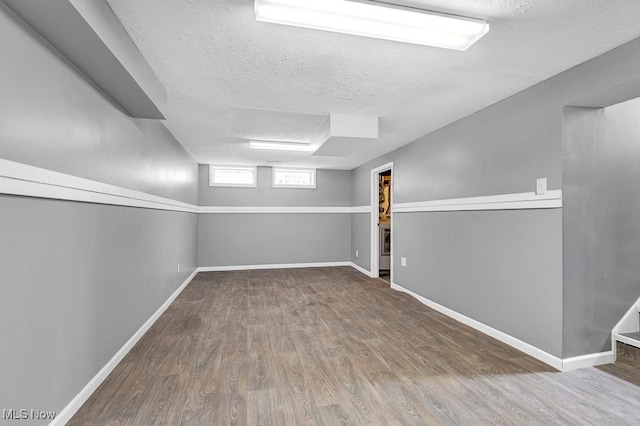 basement featuring wood-type flooring and a textured ceiling