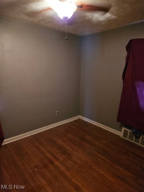 unfurnished room featuring dark wood-type flooring and a textured ceiling