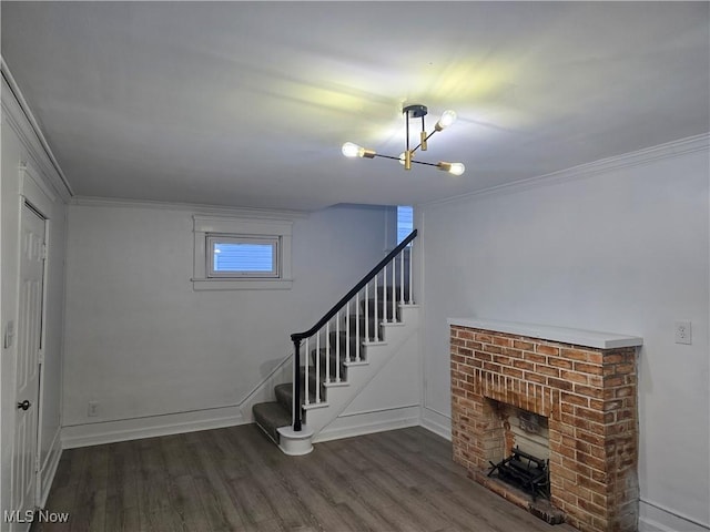 basement featuring dark hardwood / wood-style flooring, a brick fireplace, crown molding, and an inviting chandelier