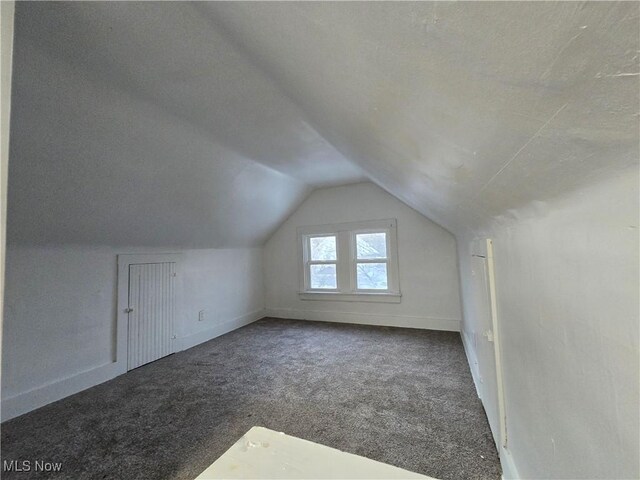 bonus room with vaulted ceiling and dark carpet