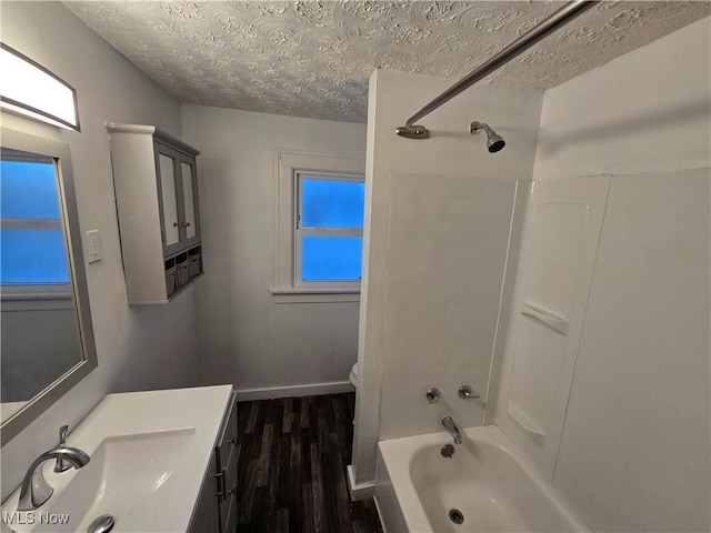 full bathroom featuring hardwood / wood-style floors, vanity, toilet, a textured ceiling, and washtub / shower combination