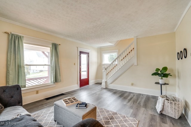 living room with crown molding, wood-type flooring, and a textured ceiling