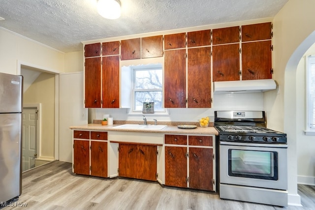 kitchen featuring sink, light hardwood / wood-style floors, a textured ceiling, and appliances with stainless steel finishes