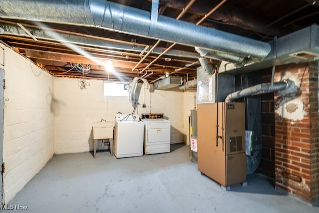 basement featuring water heater, separate washer and dryer, sink, and heating unit