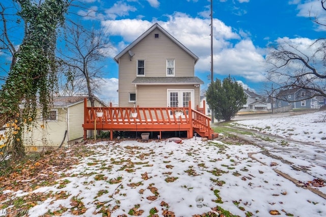 snow covered back of property featuring a deck