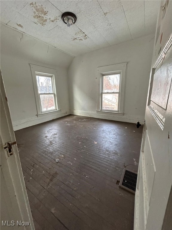 empty room featuring vaulted ceiling and dark hardwood / wood-style floors