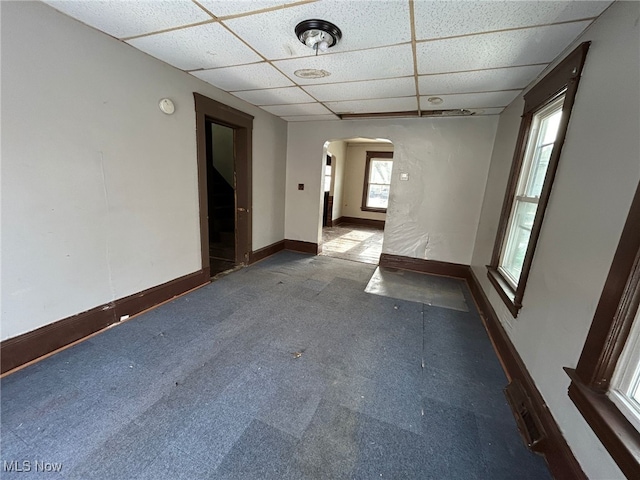 carpeted spare room featuring a drop ceiling