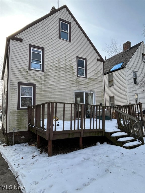 snow covered back of property featuring a wooden deck