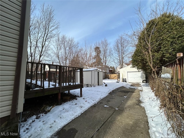 snow covered deck featuring a garage and a shed