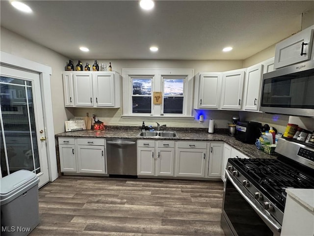 kitchen featuring wood-type flooring, appliances with stainless steel finishes, sink, and white cabinets