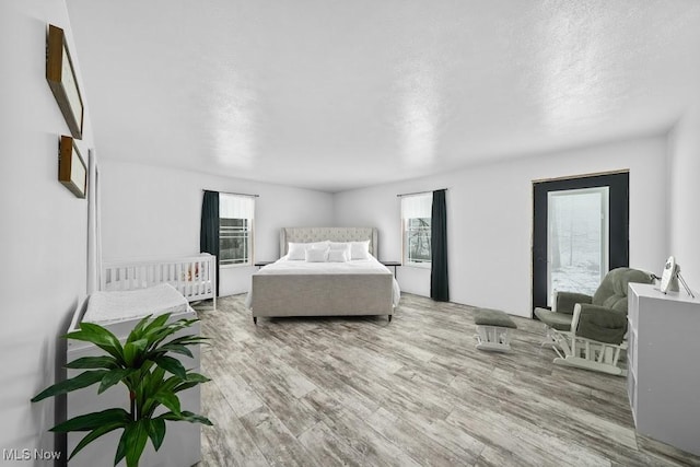 bedroom featuring multiple windows, a textured ceiling, and light wood-type flooring