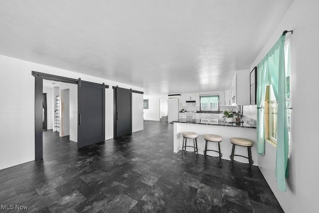 kitchen with white refrigerator, a barn door, white cabinets, and kitchen peninsula