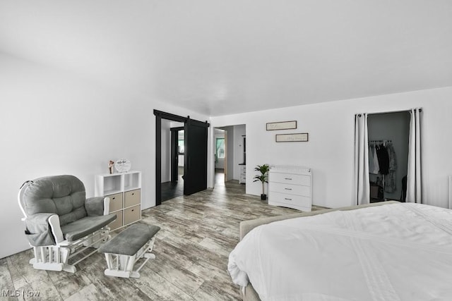 bedroom featuring a barn door, light hardwood / wood-style floors, and a closet