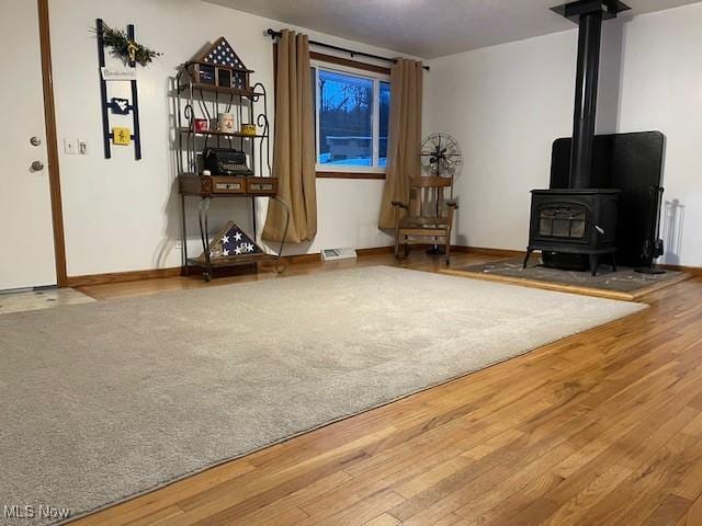 sitting room featuring hardwood / wood-style flooring and a wood stove