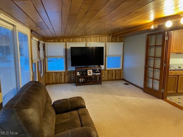 carpeted living room featuring wood ceiling and wooden walls