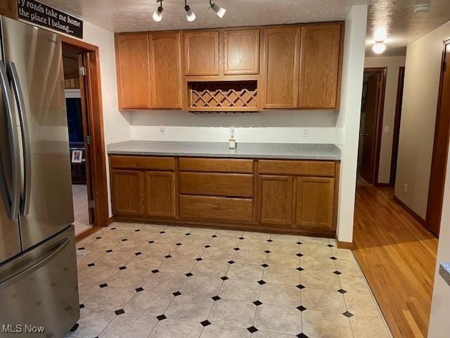 kitchen with track lighting, stainless steel refrigerator, and a textured ceiling