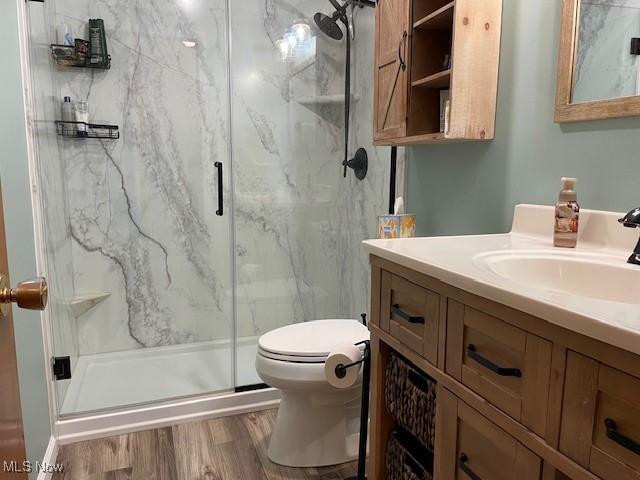 bathroom with vanity, hardwood / wood-style floors, a shower with door, and toilet