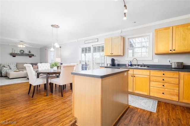 kitchen with sink, ornamental molding, a kitchen island, decorative light fixtures, and light wood-type flooring