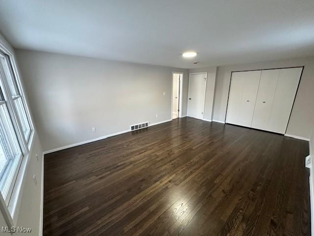 unfurnished bedroom featuring multiple windows and dark hardwood / wood-style floors