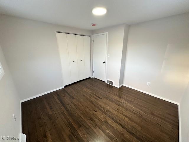 unfurnished bedroom with dark hardwood / wood-style flooring and a closet