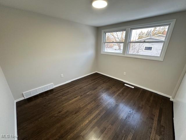 unfurnished room with a healthy amount of sunlight and dark hardwood / wood-style floors