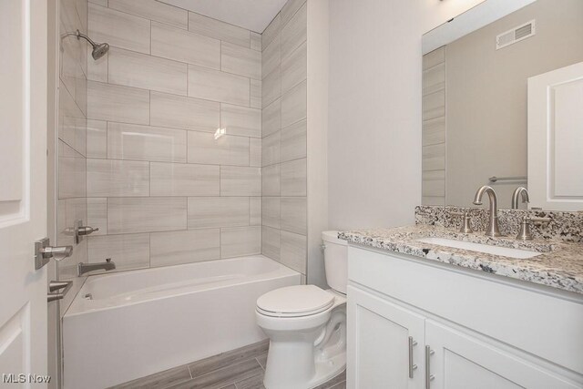 full bathroom featuring hardwood / wood-style flooring, vanity, toilet, and tiled shower / bath combo