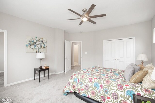 bedroom featuring light colored carpet, ceiling fan, and a closet