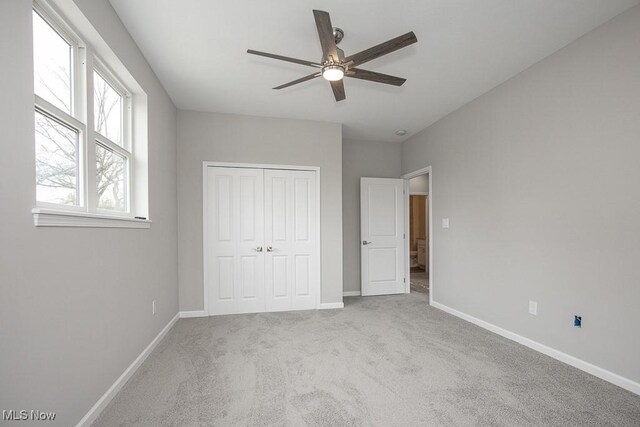 unfurnished bedroom featuring light carpet, ceiling fan, and a closet