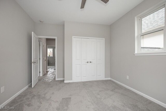 unfurnished bedroom featuring ceiling fan, light colored carpet, and a closet