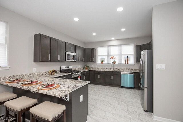 kitchen featuring appliances with stainless steel finishes, a kitchen bar, kitchen peninsula, and sink