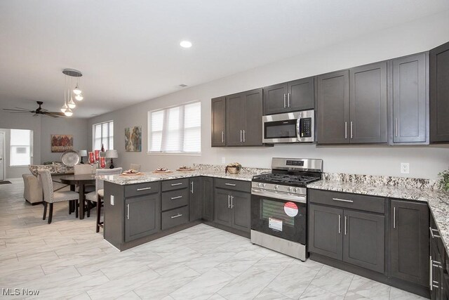 kitchen featuring pendant lighting, kitchen peninsula, ceiling fan, light stone counters, and stainless steel appliances