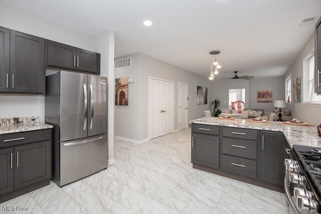 kitchen with stainless steel appliances, ceiling fan, pendant lighting, and light stone counters