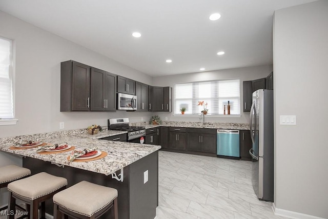 kitchen with stainless steel appliances, a kitchen bar, kitchen peninsula, and sink