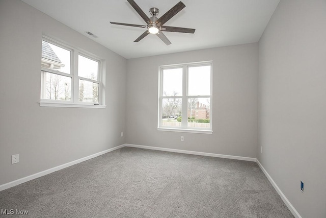 empty room featuring ceiling fan, carpet floors, and a wealth of natural light