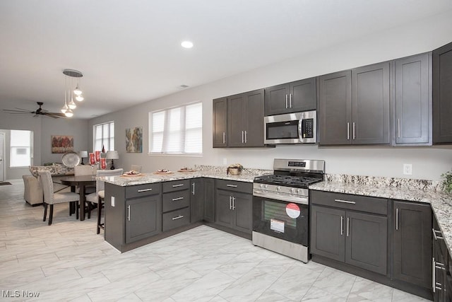 kitchen featuring appliances with stainless steel finishes, light stone counters, ceiling fan, kitchen peninsula, and hanging light fixtures