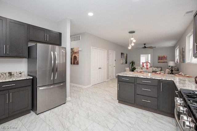 kitchen with appliances with stainless steel finishes, light stone countertops, ceiling fan, and decorative light fixtures