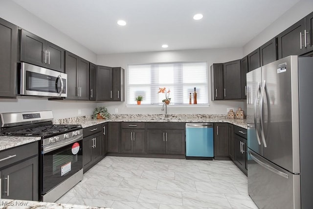 kitchen with sink, appliances with stainless steel finishes, and light stone countertops