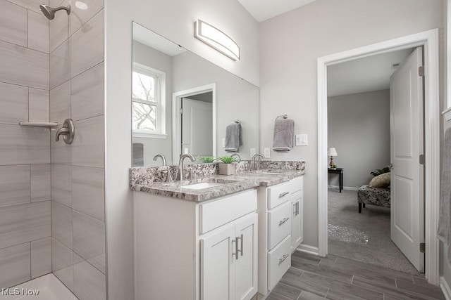 bathroom with tiled shower and vanity