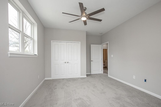 unfurnished bedroom with ceiling fan, light carpet, and a closet