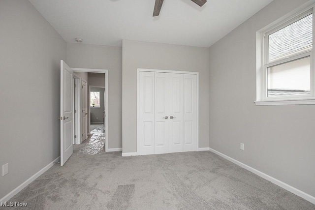 unfurnished bedroom with light carpet, a closet, and ceiling fan