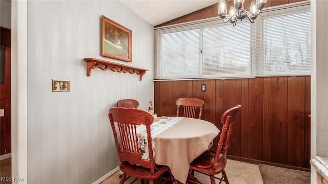 dining area featuring a chandelier, vaulted ceiling, and wood walls