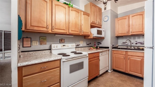 kitchen featuring white appliances, light stone countertops, and sink