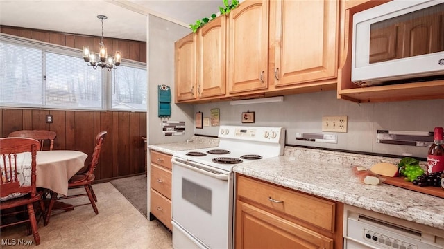 kitchen with wooden walls, hanging light fixtures, a notable chandelier, light stone countertops, and white appliances