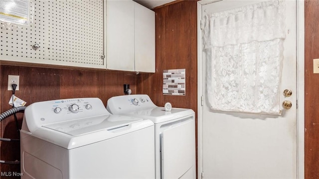 washroom with cabinets, washer and dryer, and wood walls