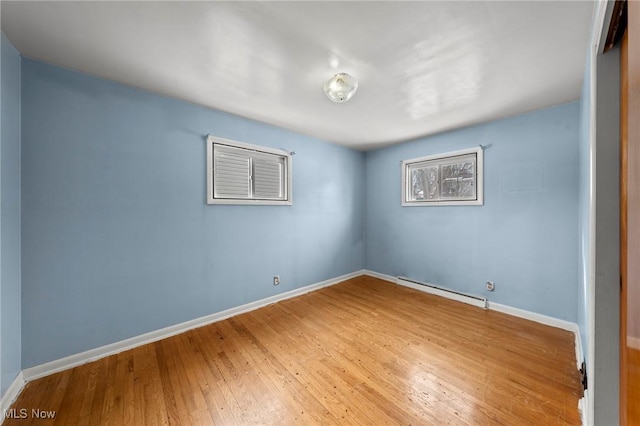 spare room featuring wood-type flooring and a baseboard heating unit