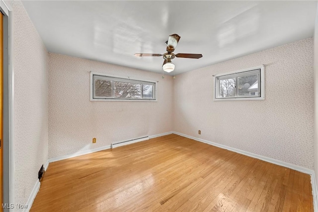 unfurnished room featuring a healthy amount of sunlight, light wood-type flooring, and a baseboard heating unit