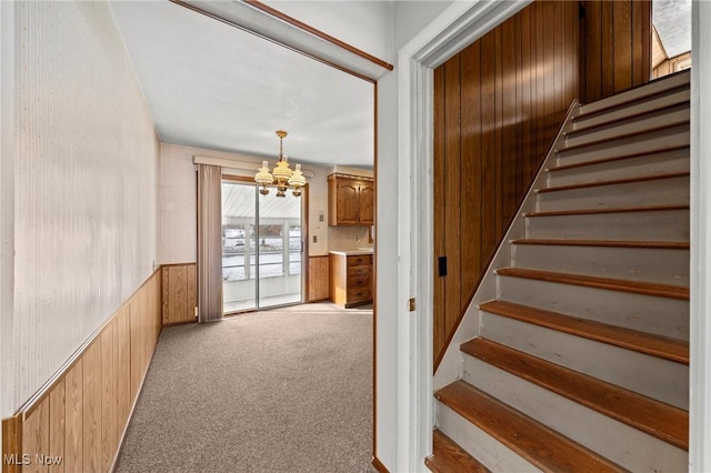 staircase with carpet floors and a notable chandelier